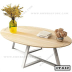 Modern oval wooden center table with metallic legs, yellow vase, books, and flowers