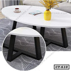 Modern oval white center table with black legs, yellow vase and cup, on patterned rug