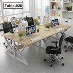 Modern four-person office desk setup with chairs, partitions, computers, and plants