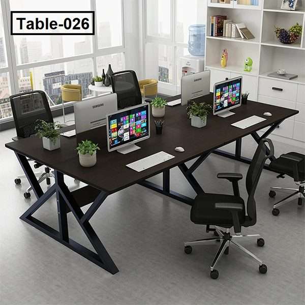 Modern four-person office desk with computers, mesh chairs, and indoor plants in workspace