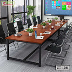 Modern conference room with large wooden meeting table, black chairs, laptops, and potted plants