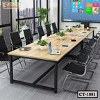 Modern conference room with large wooden meeting table, black chairs, and office laptops
