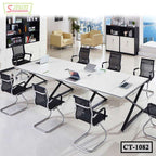 Modern office conference table with black chairs, laptops, and shelves in a bright meeting room