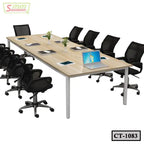 Modern office conference table with mesh chairs, laptops, notebooks, and decorative plants.
