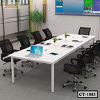 Modern white conference table with black office chairs, laptops, and plants in a meeting room