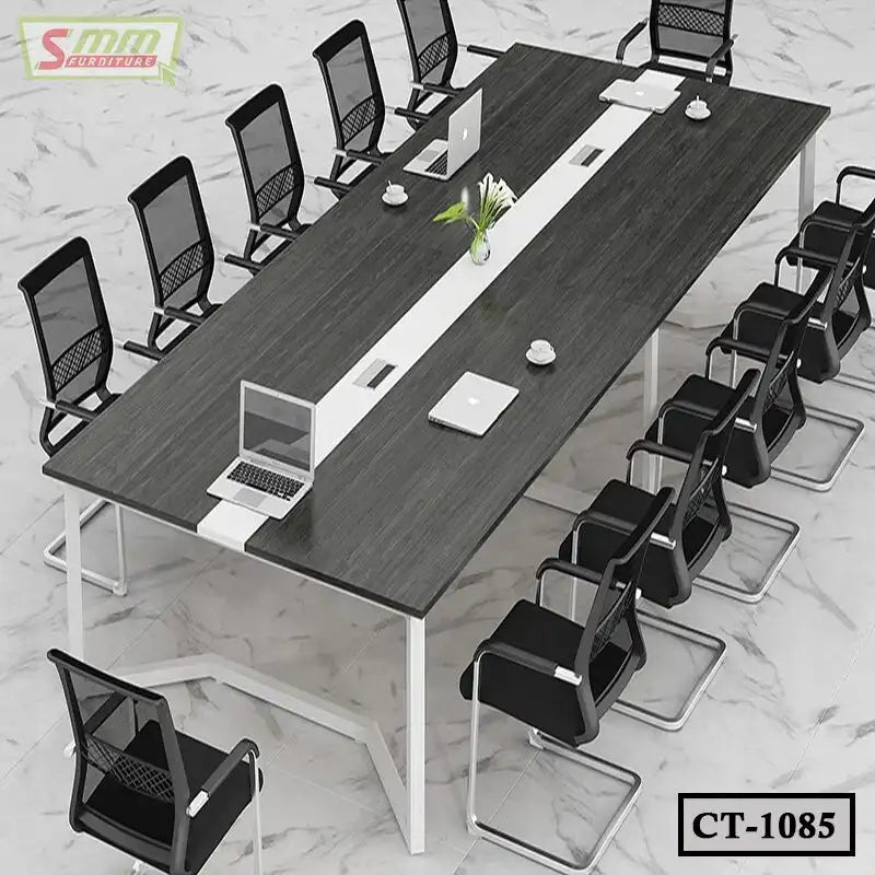 Modern conference table with black chairs, laptops, and coffee cups in a meeting room