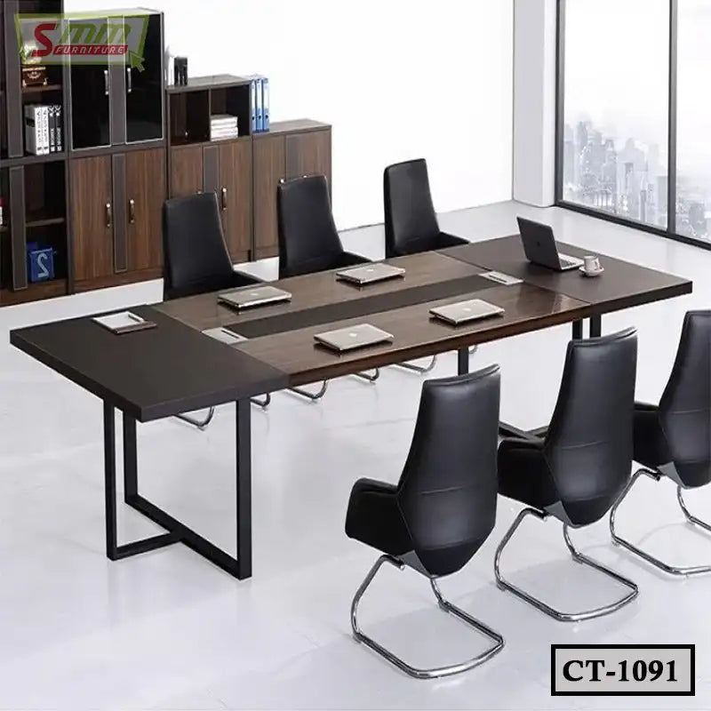 Modern conference table with black chairs, laptops, and cabinets in a bright office