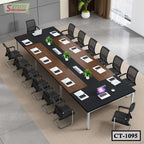 Modern conference table with black chairs, laptops, and green plants in office setting
