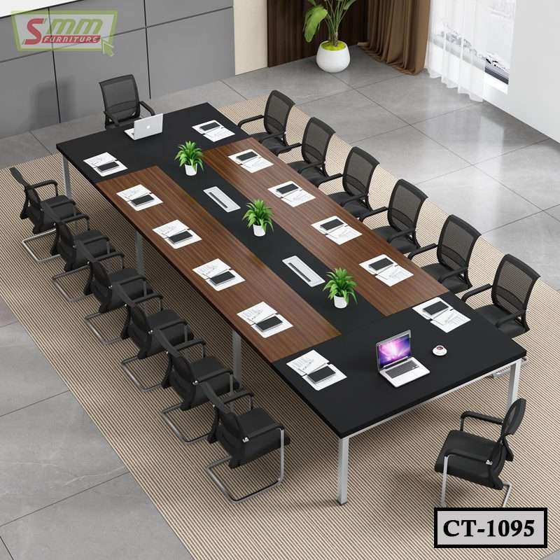 Modern conference table with black chairs, laptops, and green plants in office setting