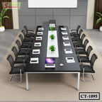 Modern black conference table with mesh chairs, laptops, documents, and decorative green plants