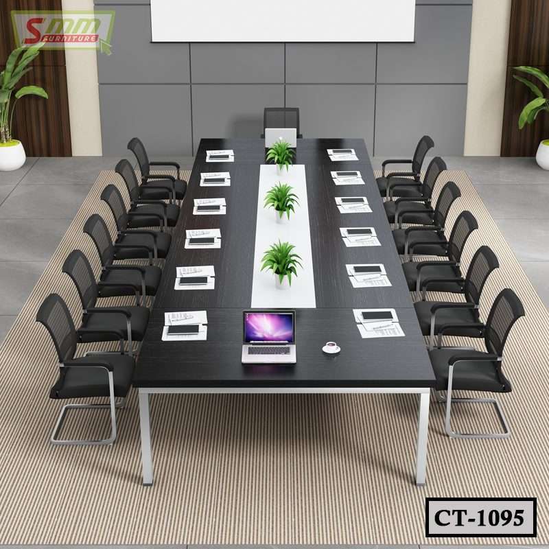 Modern black conference table with mesh chairs, laptops, documents, and decorative green plants