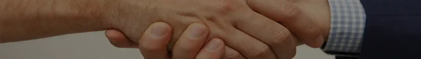Close-up handshake between two people, one in a suit, symbolizing business partnership