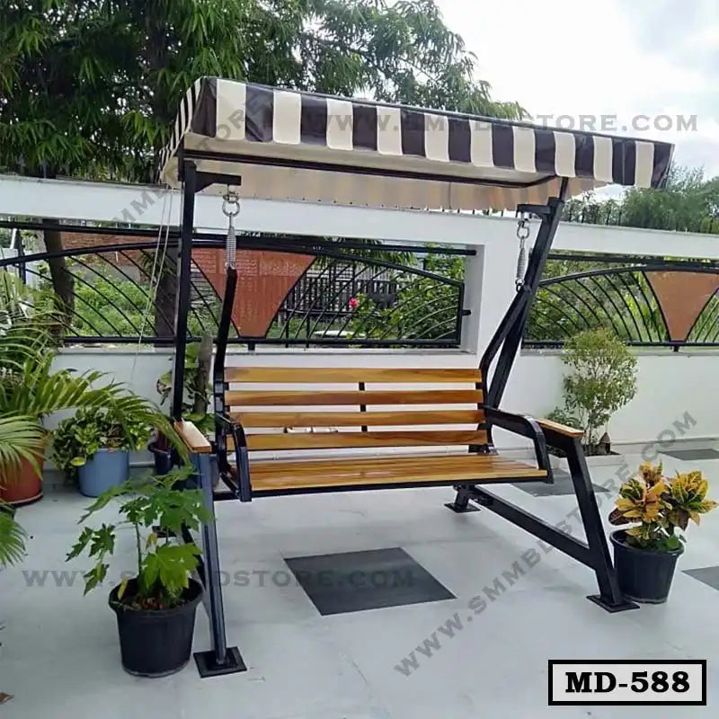 Outdoor wooden swing chair with metal frame and striped canopy on terrace with potted plants