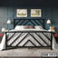 Modern double steel bed with geometric black frame in stylish bedroom, wall lamps and artwork above.