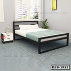 Modern double steel bed with white bedding in a bright bedroom with side table and indoor plant.