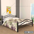 Black metal double bed with decorative frame and printed bedding in a modern bedroom