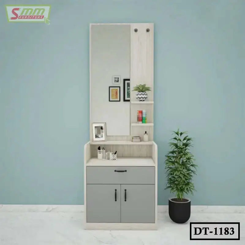 Modern wooden dressing table with large mirror, gray storage cabinets, and shelves, next to a potted plant.