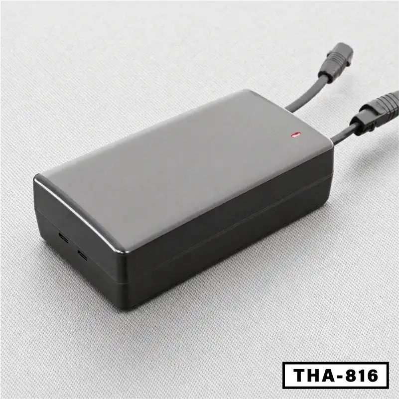 Black electric folding desk power adapter with connected cables, model THA-816, on gray surface.