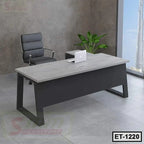 Modern executive office table with grey tabletop, black frame, office chair, and indoor plant