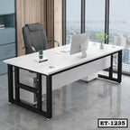 Modern executive office table with black metal legs, white tabletop, and ergonomic chair in a high-rise office setting.