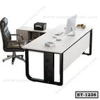 Modern executive office table with L-shaped desk, black chair, and computer setup