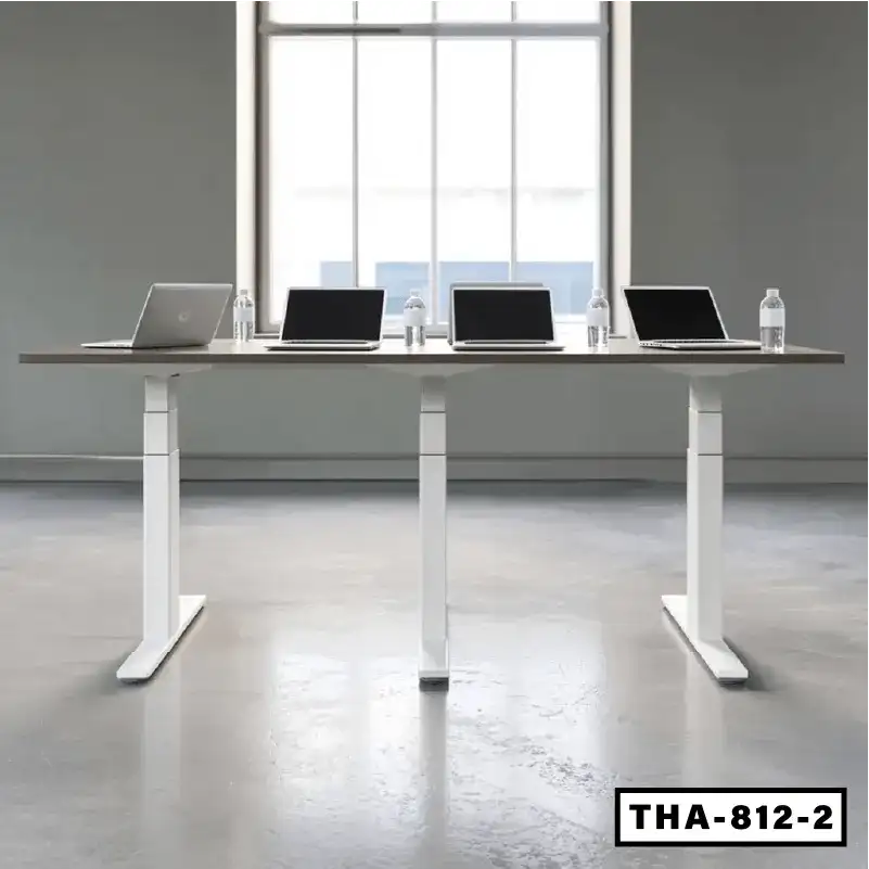 Height adjustable conference table with sleek white legs, laptops, and water bottles in modern office setting.
