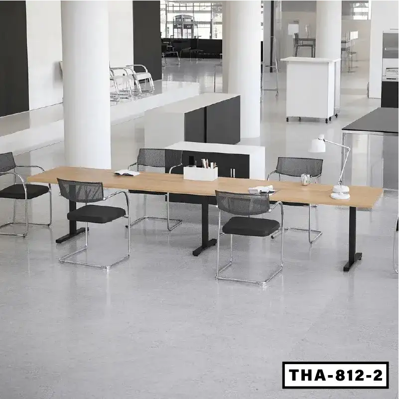 Modern height-adjustable conference table with black frame and mesh office chairs in a bright workspace.