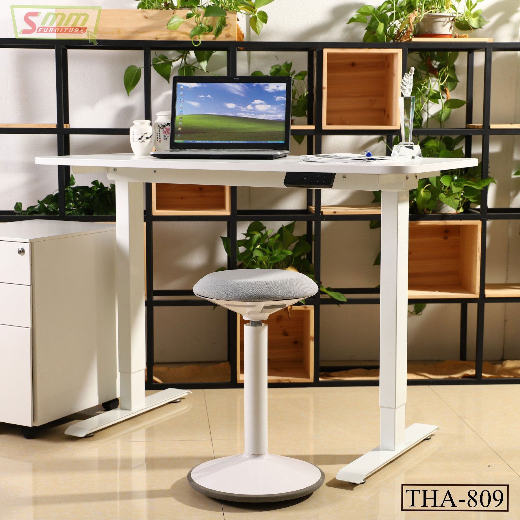 Modern height-adjustable white desk with laptop and ergonomic stool in a home office setting