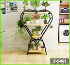 Heart-shaped metal and wood plant stand with multiple potted plants in a modern living room.