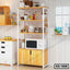 Modern wooden kitchen storage rack with shelves, microwave, and kitchenware beside a window