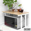 Wooden kitchen shelf organizer with microwave underneath, bottles and plant on top