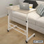 Adjustable laptop table with wheels beside a modern sofa in a home office setting