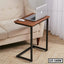 Wooden laptop table with metal frame beside beige sofa in living room