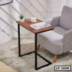 Modern laptop table with wooden top and metal frame beside a grey armchair in a cozy room