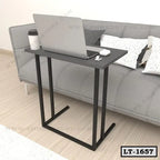 Modern black laptop table near a grey sofa and pillows in a home office setting