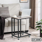 Modern rolling laptop table beside beige sofa in living room, with cup and laptop on top