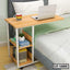 Adjustable laptop table with storage shelves beside bed, featuring books, plant, and coffee mug.