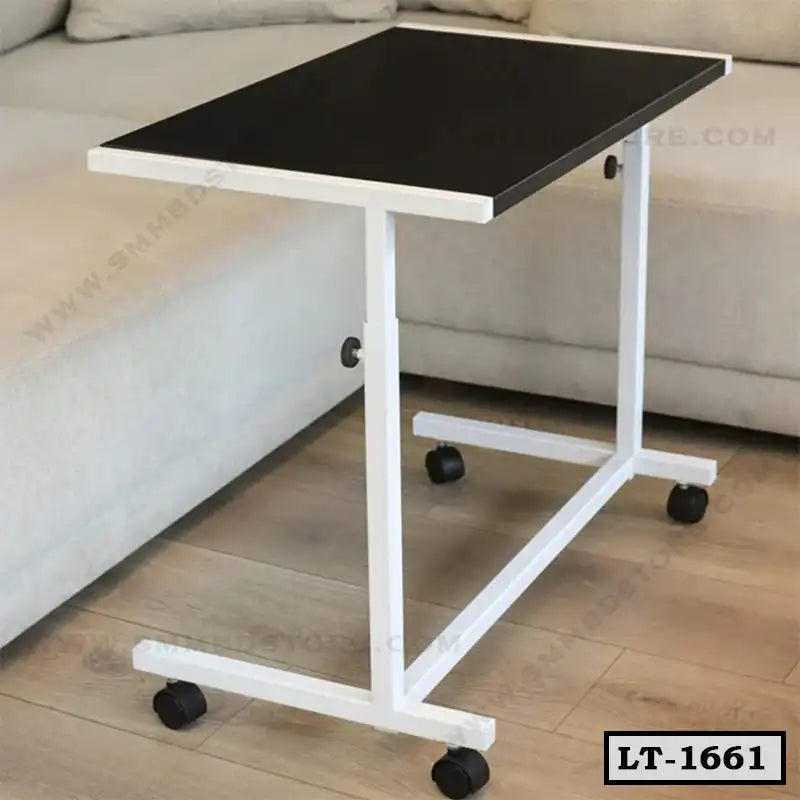 Adjustable laptop table with black top and white metal frame on wheels beside sofa