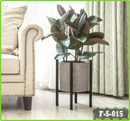 Modern metal flower stand with potted plant beside a sofa in a bright living room