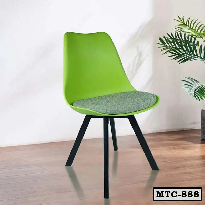 Modern green metal tulip chair with gray cushion, black legs, on wooden floor near plant