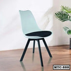 Modern metal tulip chair with black cushioned seat on wooden floor, indoor plant nearby