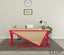 Modern office desk with red metal frame, light wood top, and workspace accessories in a minimalist room.