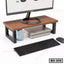 Wood and metal monitor stand with storage space for books, ideal for office desktop setup.
