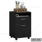 Modern black office drawer unit with wheels, two drawers, open shelf, and decorative items on top.