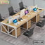 Modern office workstation with four wooden desks, computers, partition panels, and black chairs