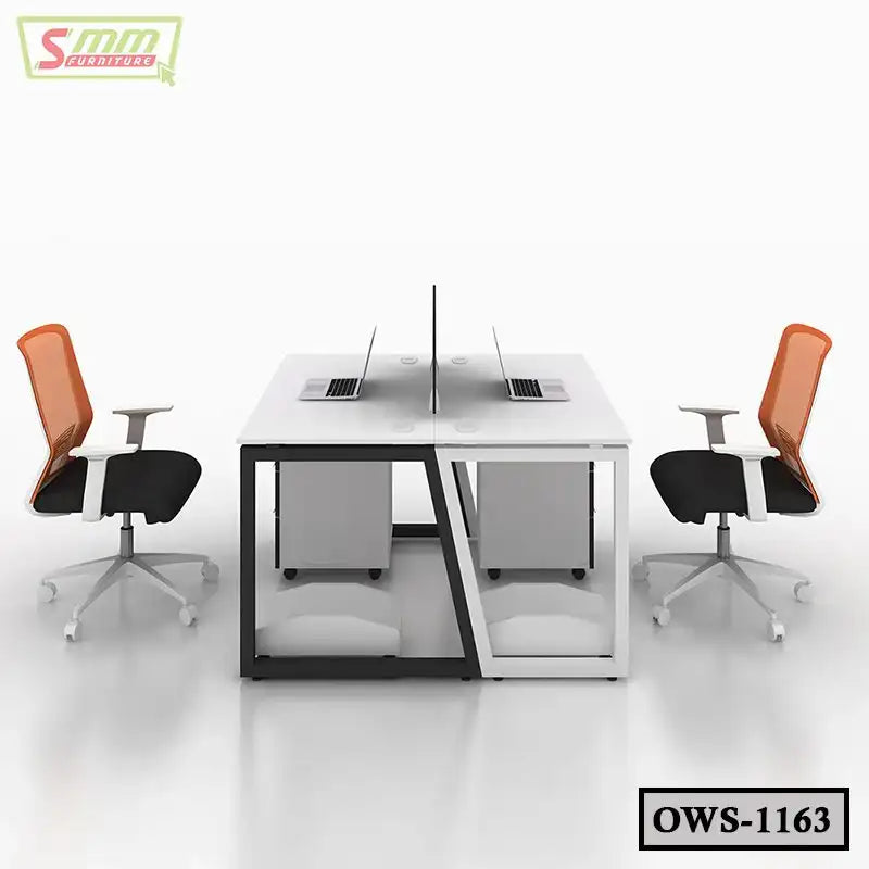 Modern office workstation with two orange mesh chairs, white desks, laptops, and privacy divider.