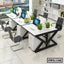 Modern office workstation with white desks, black chairs, computers, and indoor plants