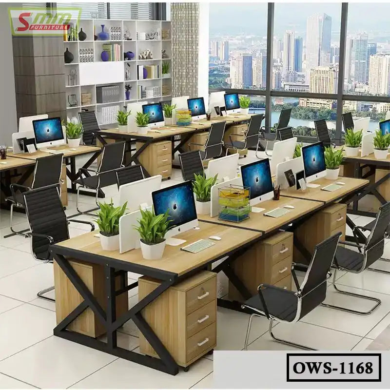 Modern office workstation setup with multiple desks, computers, office chairs, and indoor plants.