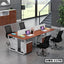 Modern office workstation desk for four with chairs, laptops, and storage cabinets in open workspace