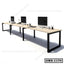 Modern office workstation desk with computers and accessories on a long wooden table